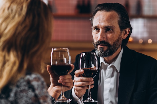 L&#39;uomo di mezza età guarda la donna e alza un bicchiere di vino rosso con lei