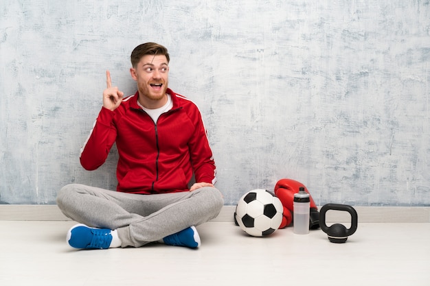 L'uomo di sport di Redhead che intende realizzare la soluzione mentre solleva un dito su