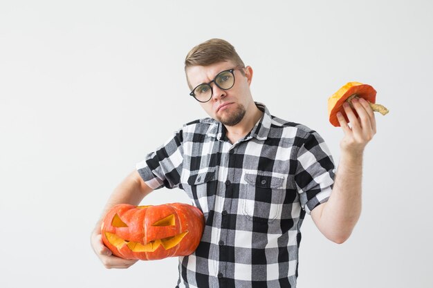 L'uomo divertente felice che tiene un jack o lantern ha intagliato la zucca di Halloween nella stanza luminosa.