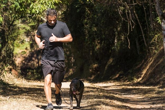 l'uomo e il suo cane pitbull corrono sulla strada sterrata lui e il pitbull si esercitano