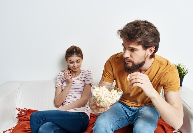 L'uomo e la bella donna sono seduti sul divano davanti al fiore degli amici di famiglia TV in una pentola