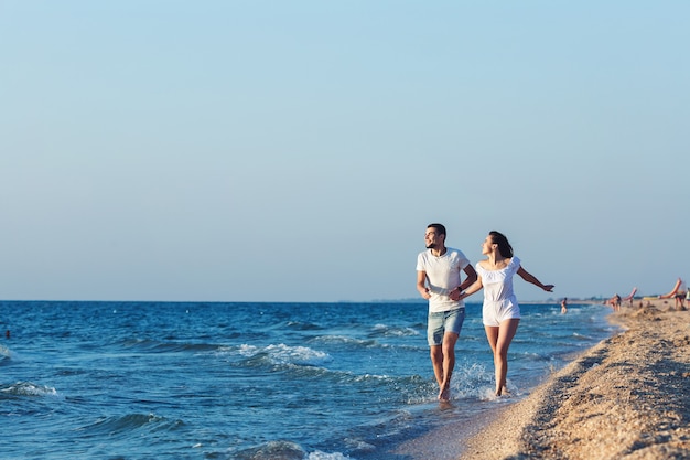 L'uomo e la donna corrono felici lungo la costa del mare.