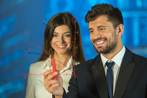 L'uomo e la donna felici che disegnano sullo schermo virtuale