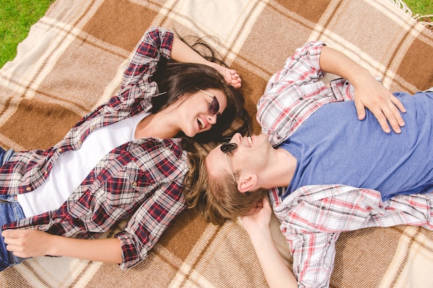 L'uomo e la donna felici con gli occhiali da sole giacevano a terra