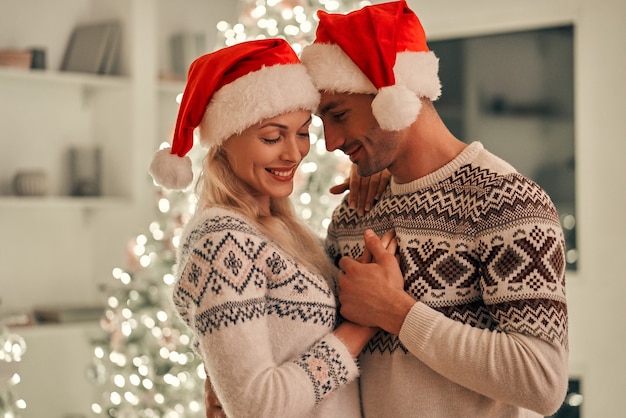 L'uomo e la donna felici in piedi sullo sfondo dell'albero di Natale