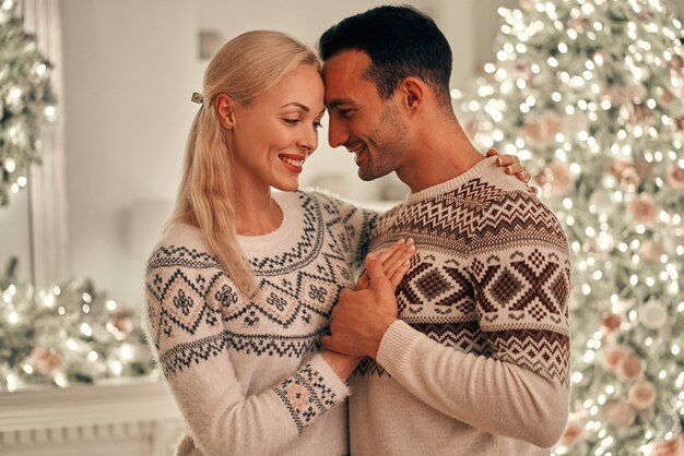 L'uomo e la donna felici in piedi sullo sfondo dell'albero di Natale