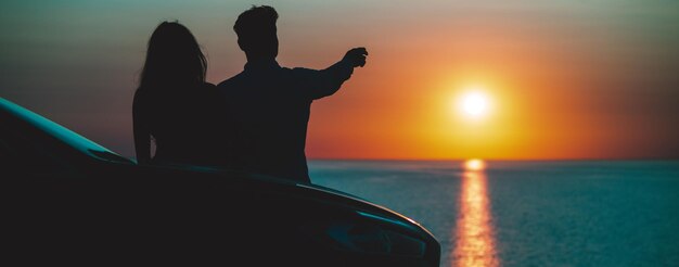 L'uomo e la donna in piedi vicino alla macchina sul bellissimo sfondo della riva del mare