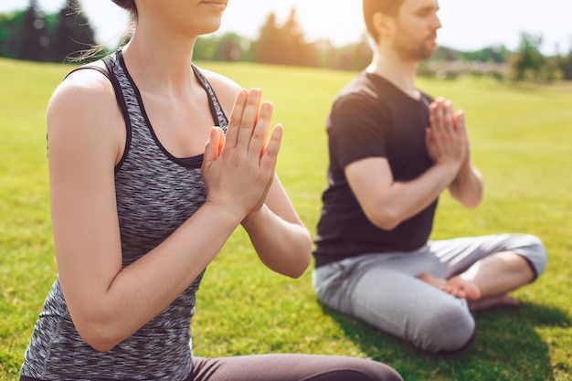 L'uomo e la donna praticano l'acro yoga nella meditazione del parco