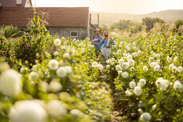 L'uomo e la donna raccolgono fiori in fattoria all'aperto ampia vista