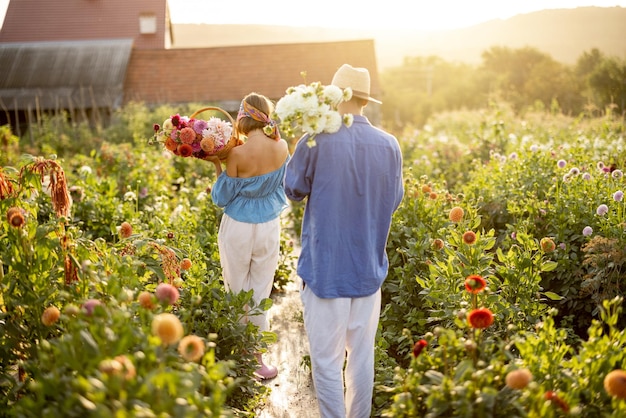 L'uomo e la donna raccolgono i fiori in una fattoria all'aperto