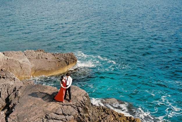 L'uomo e la donna sono in piedi su una scogliera rocciosa in riva al mare