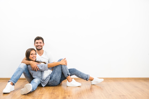 L'uomo e la donna sorridenti si siedono sullo sfondo del muro vuoto