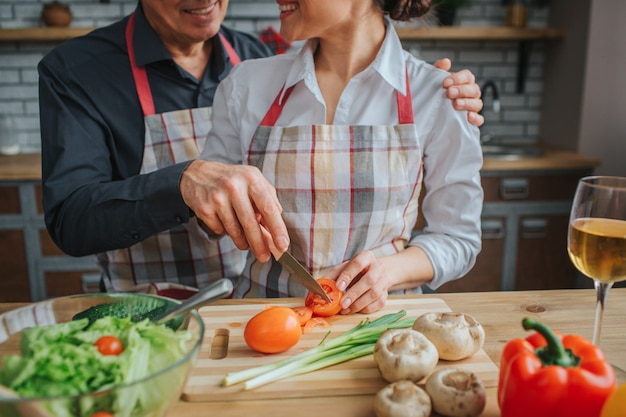 L'uomo e la donna stanno insieme e cucinano alla tavola in cucina