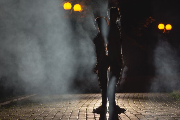 L'uomo e la donna stanno sulla strada fumosa. notte