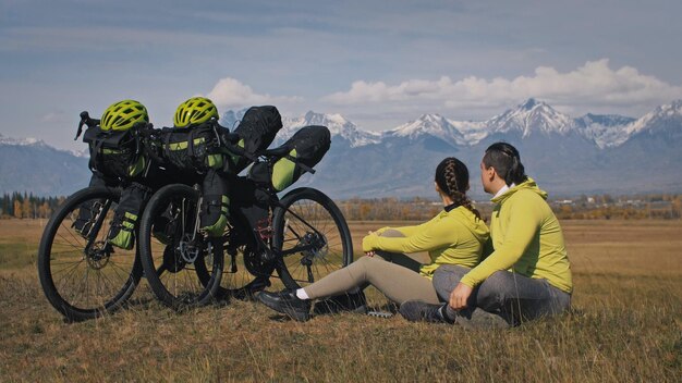 L'uomo e la donna viaggiano su terreno misto cicloturismo con bikepacking Le due persone viaggiano con borse da bicicletta Montagna innevata