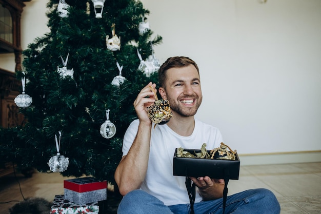 L'uomo è seduto a casa vicino all'albero di Natale