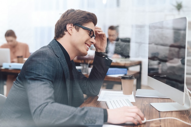 L'uomo è seduto al computer e lavora.