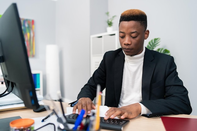 L'uomo elegante che lavora in un ragazzo dello studio legale dell'ufficio si siede dietro la scrivania davanti al computer