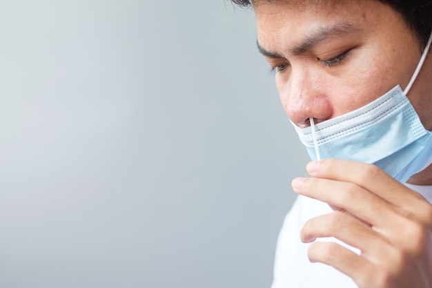 L'uomo esegue il test COVID-19 con tampone per test rapido dell'antigene. Coronavirus Auto nasale o test a casa, concetto di blocco e isolamento domestico