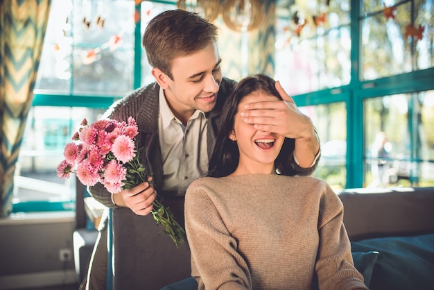 L'uomo fa una sorpresa con i fiori per una donna al ristorante