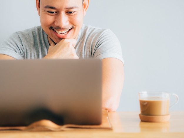 L&#39;uomo faccia felice lavora sul suo computer portatile.