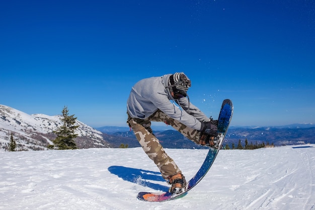 L'uomo facendo snowboard salto sullo sfondo delle montagne