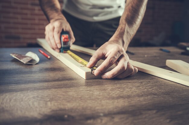 L'uomo falegname misura la tavola di legno