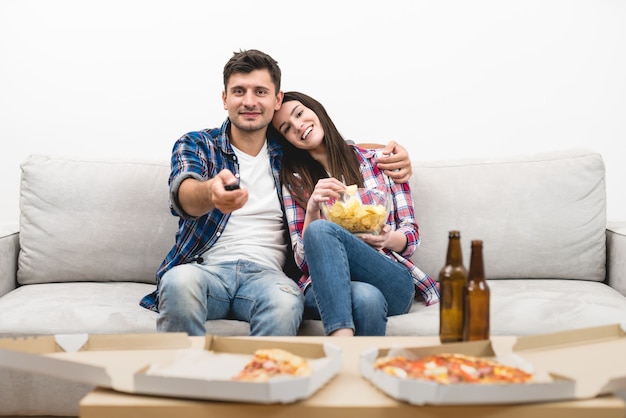 L'uomo felice e una donna guardano la televisione sullo sfondo del muro bianco