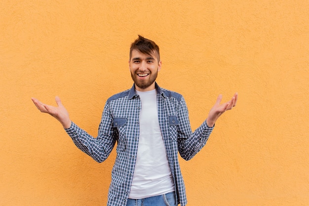 L'uomo felice fa un gesto della mano sullo sfondo di un muro arancione