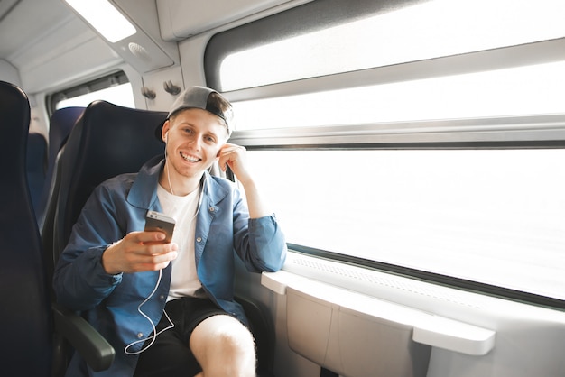 L'uomo felice sale su un treno, ascolta la musica in cuffia, tiene il telefono in mano