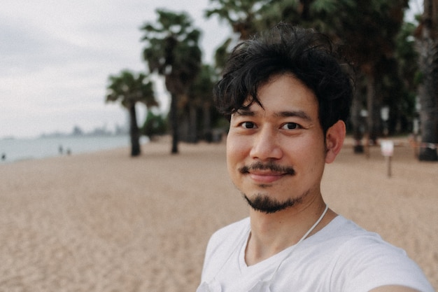 L'uomo felice si fa il selfie con la palma sulla spiaggia