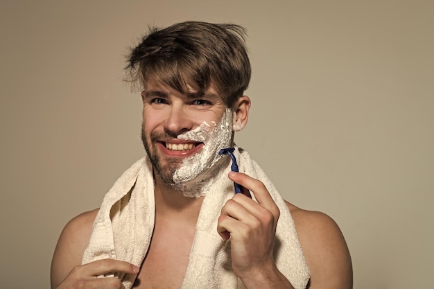 L'uomo felice si fa la barba con la barba su sfondo grigio