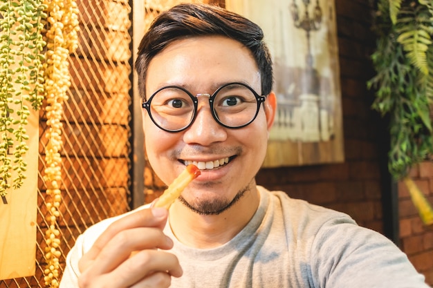 L'uomo felice sta mangiando le patate fritte nel caffè.