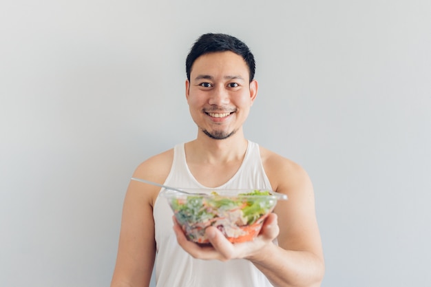 L&#39;uomo felice sta presentando il pasto sano dell&#39;insalata.