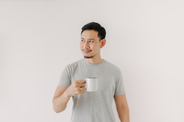 L'uomo felice tiene una tazza di caffè isolata sul muro bianco