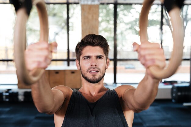 L'uomo fitness è impegnato sugli anelli in palestra