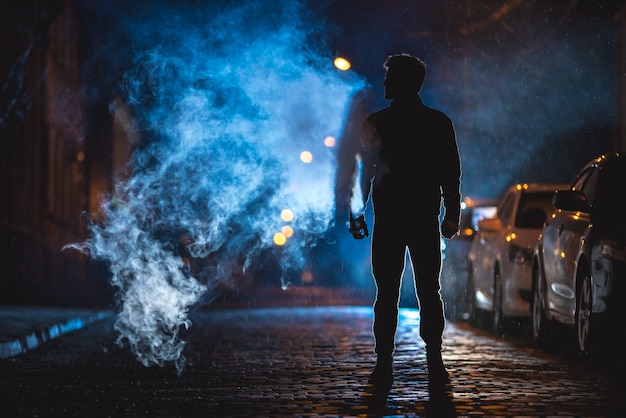 L'uomo fuma per strada. Serata notturna. Colpo con teleobiettivo