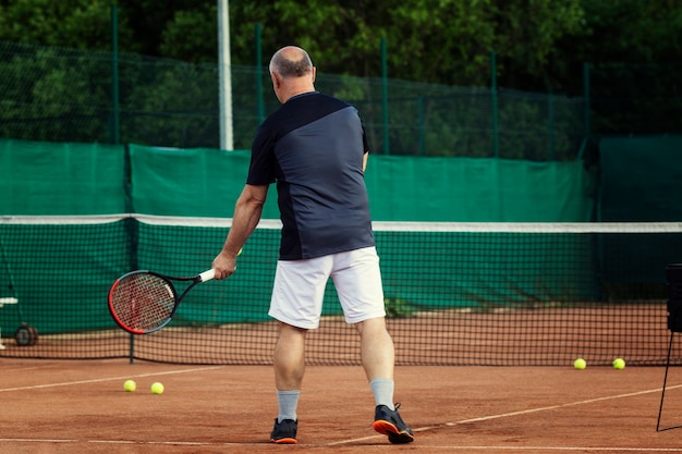 l'uomo gioca a tennis sul campo. Stile di vita attivo e salute. Vista posteriore.