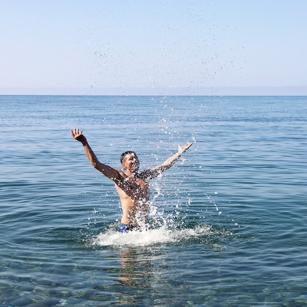 L'uomo gioioso spruzza in acqua da solo in mare