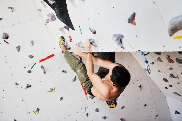 l'uomo giovane e in forma esercita l'arrampicata libera in montagna sulla parete pratica indoor