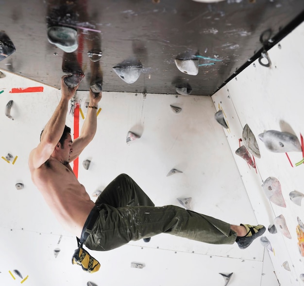 l'uomo giovane e in forma esercita l'arrampicata libera in montagna sulla parete pratica indoor