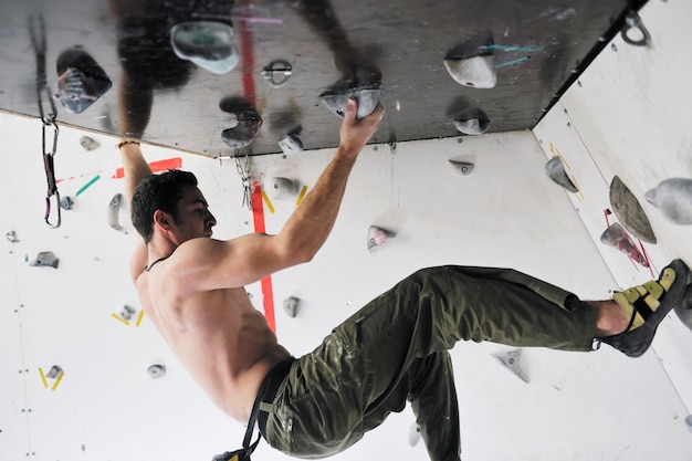 l'uomo giovane e in forma esercita l'arrampicata libera in montagna sulla parete pratica indoor