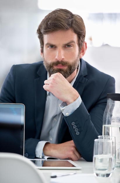 È l'uomo giusto per il lavoro. Ritratto di un giovane uomo d'affari seduto alla sua scrivania in ufficio.