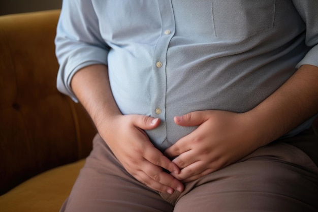 L'uomo grasso in pantaloni e camicia tiene lo stomaco con le mani Concetto di obesità e eccesso di cibo Dolore allo stomaco