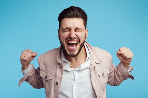 L'uomo grida con gli occhi chiusi indossa una giacca di jeans rosa