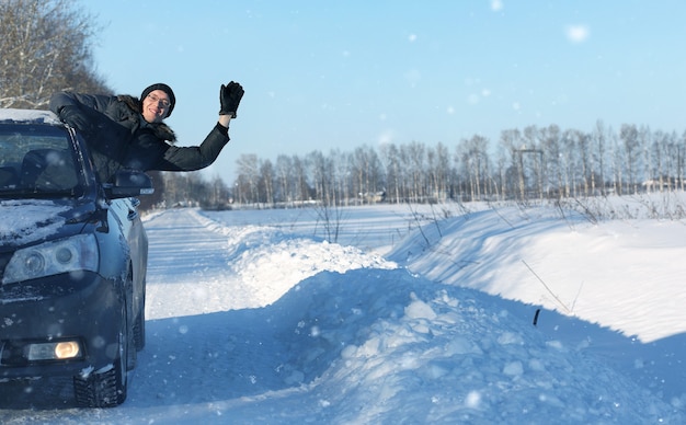 L'uomo guarda fuori dal finestrino dell'auto la strada coperta di neve nella tempesta di neve