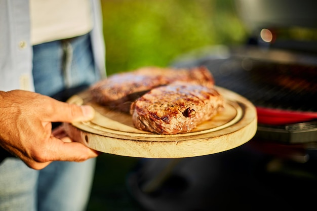 L'uomo ha posato la carne su una tavola di legno pronta da mangiare carne di bistecca alla griglia