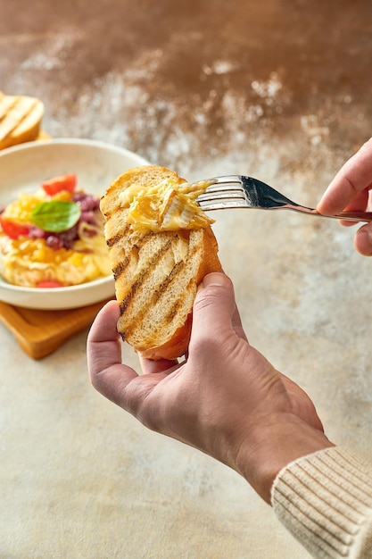 L'uomo ha spalmato il formaggio camembert al forno con cipolle e marmellata sul pane in un piatto. Primo piano, selezione