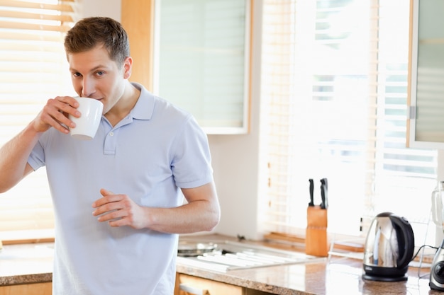 L&#39;uomo ha un sorso di caffè in cucina