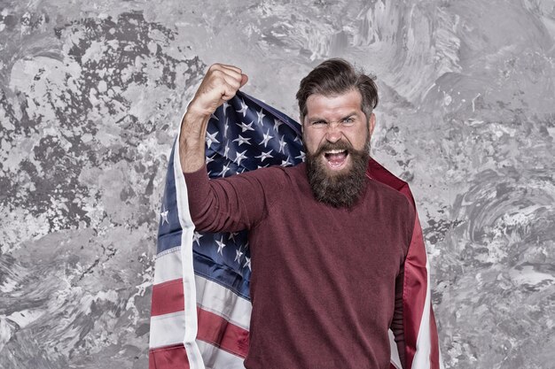 L'uomo hipster americano celebra il giorno dell'indipendenza con la bandiera nazionale, motivando il concetto di altoparlante.